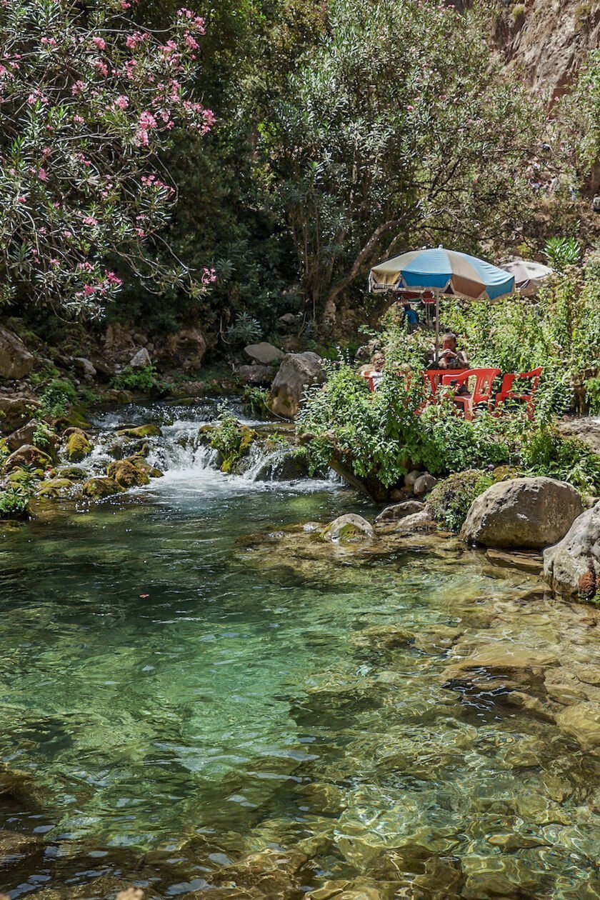 A family sit in the clear waters of a Morocco river in the Rif Mountains - one of the best destinations to visit in summer to avoid the heat. 