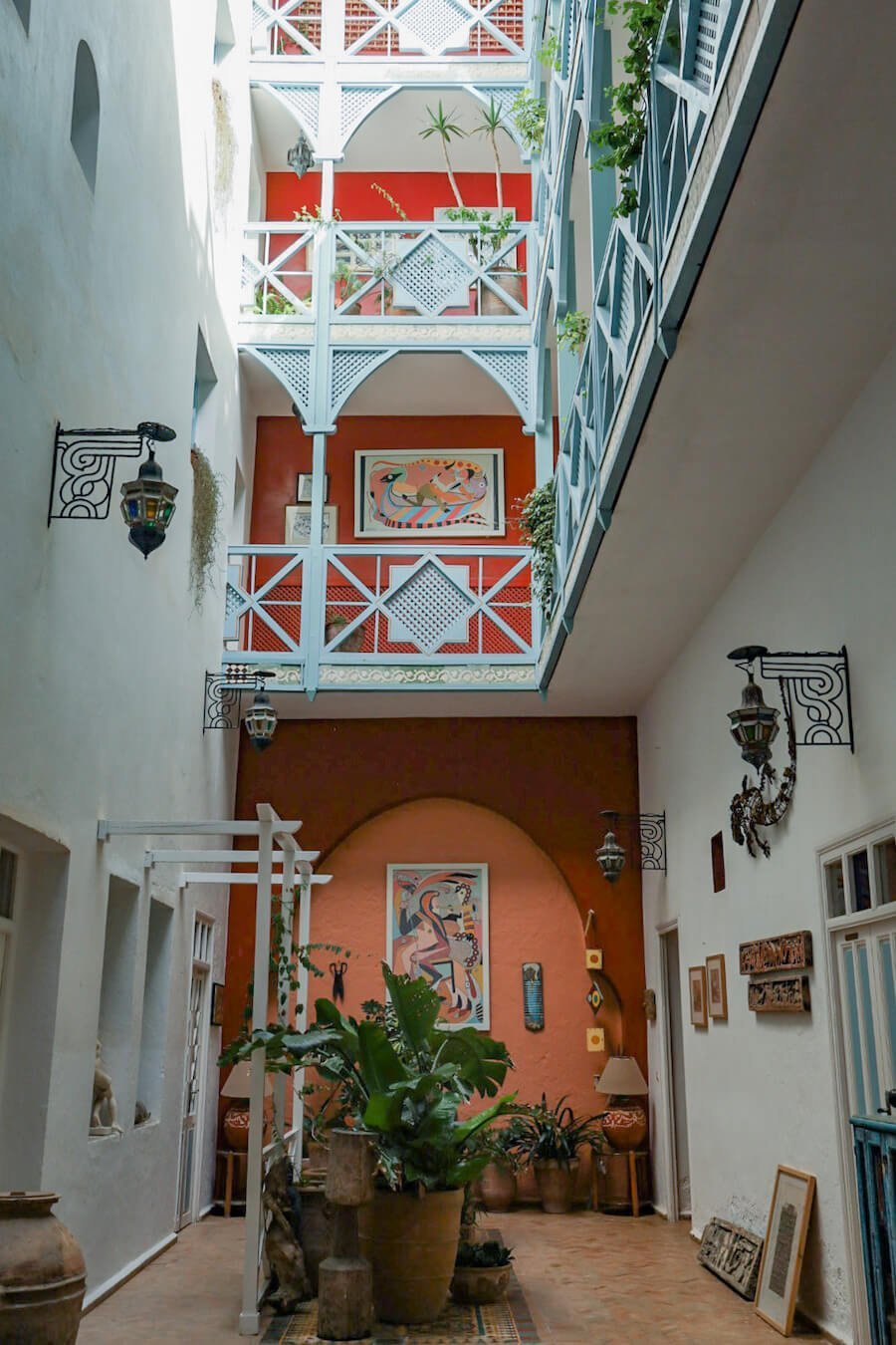 The riad courtyard interior with paintings and plants.