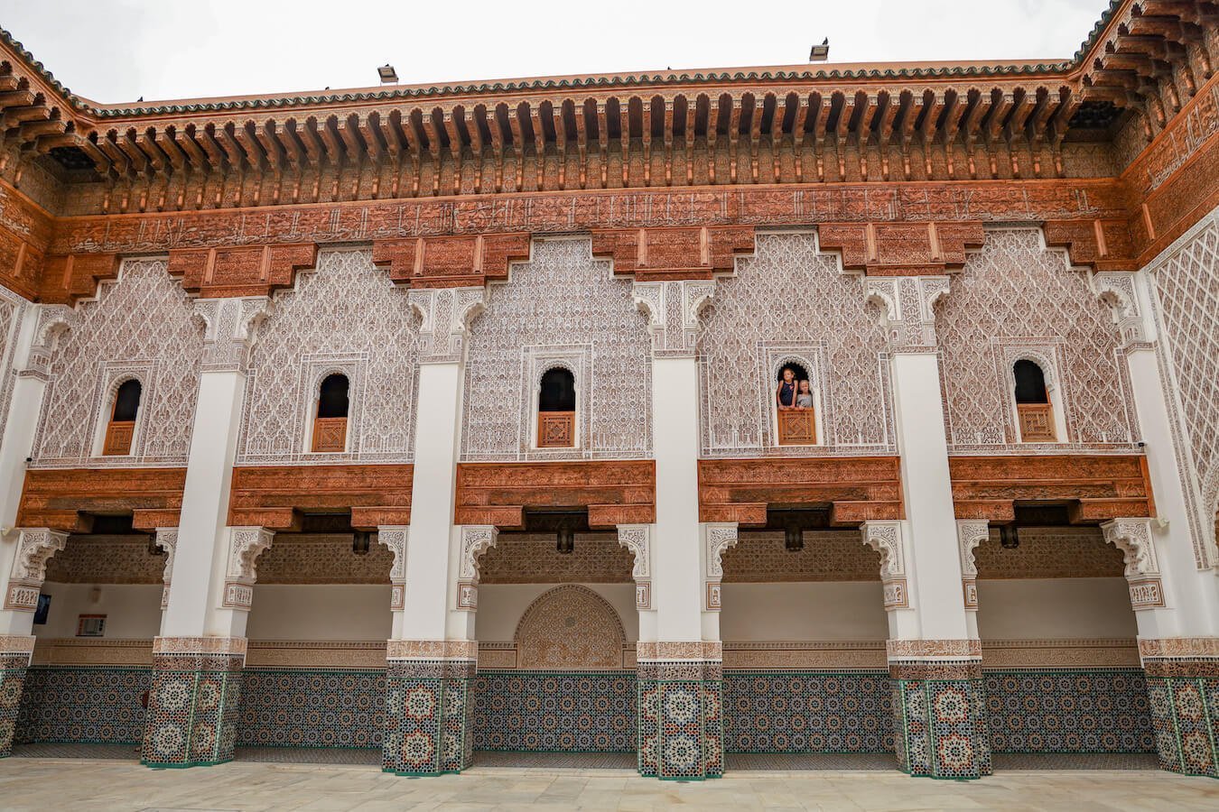 Two kids look out from the windows of the Ben Youssef Madrasa in Marrakech - one of the highlights from a Morocco travel itinerary