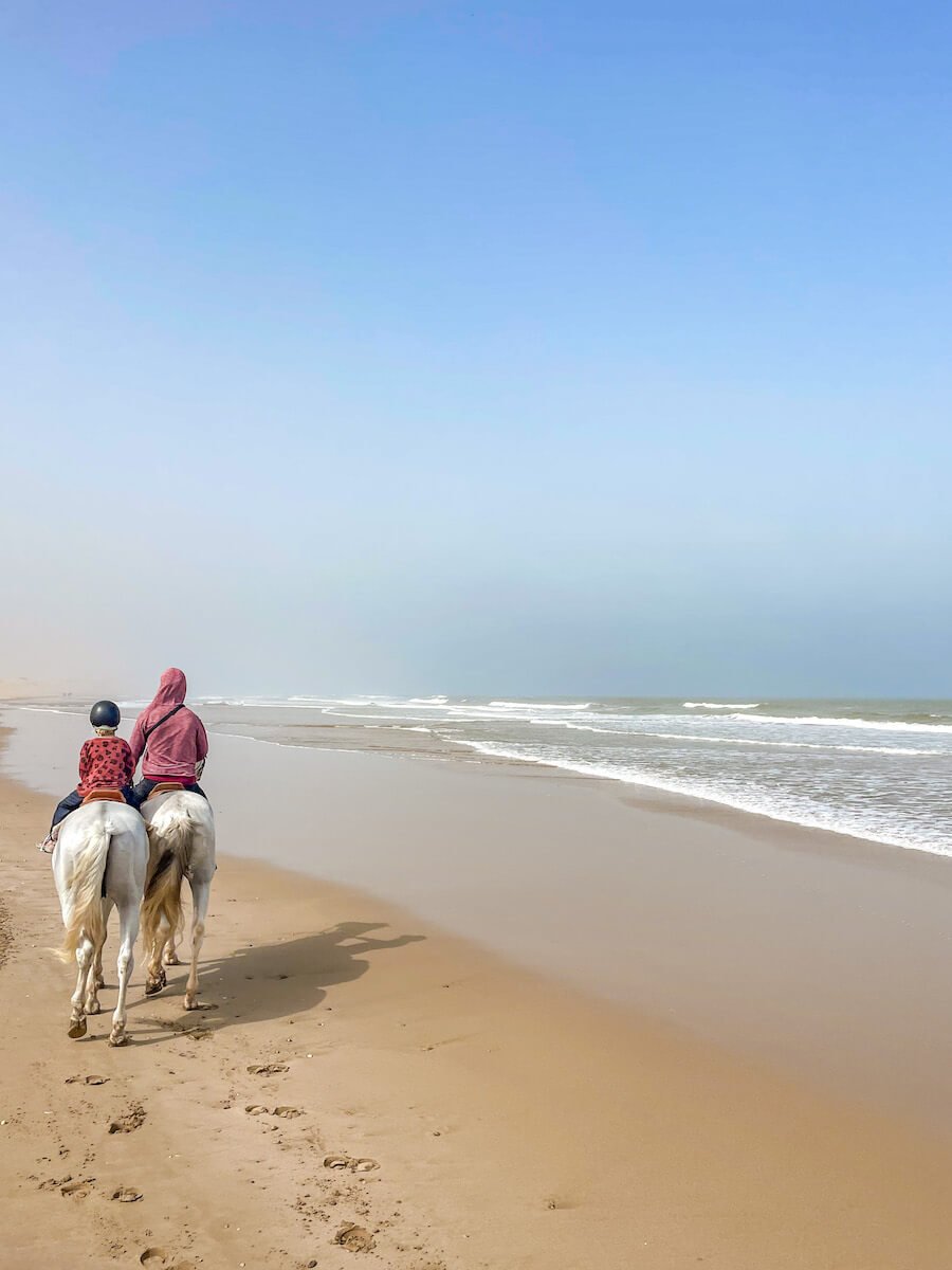 A man and a child ride a horse along the beach in Essaouira Morocco