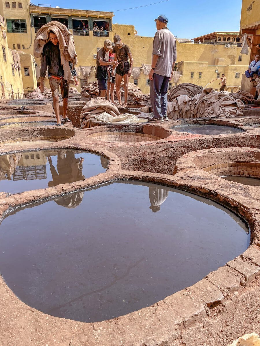 Men walk through the Chaoura Leather Tannery in Fes, a must see  on an itinerary for 14 days in Morocco
