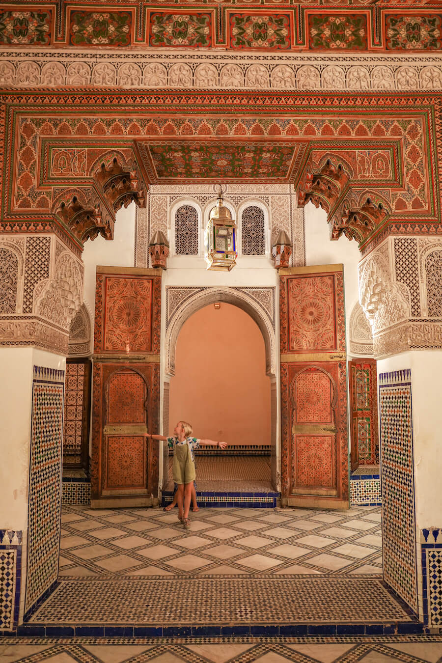 A child dances in front of an elaborate door way in the Bahia Palace in Marrakech, Morocco