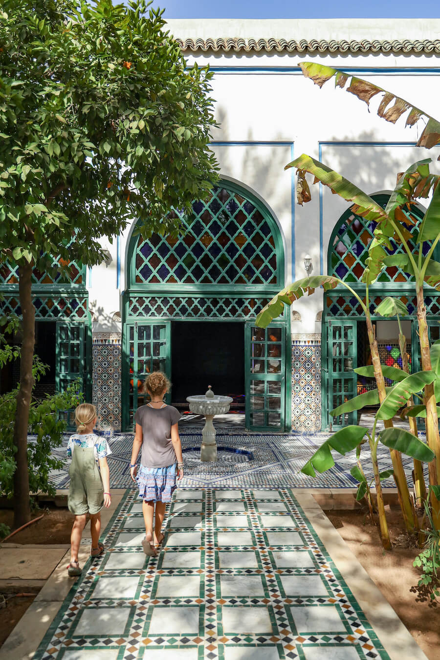 Two girls walk through a garden courtyard in the Bahia Palace in Marrakech - a popular place to go when visiting 3 days in Marrakech