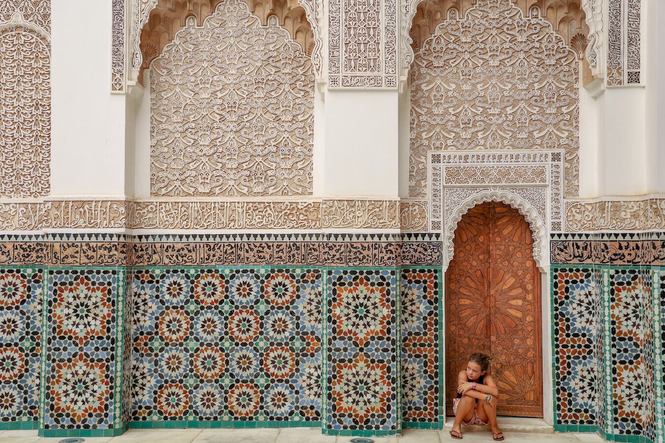 Child sits in the doorway of the beautiful Ben Youssef Madrasa in Marrakech while visiting 3 days in Marrakech, Morocco.