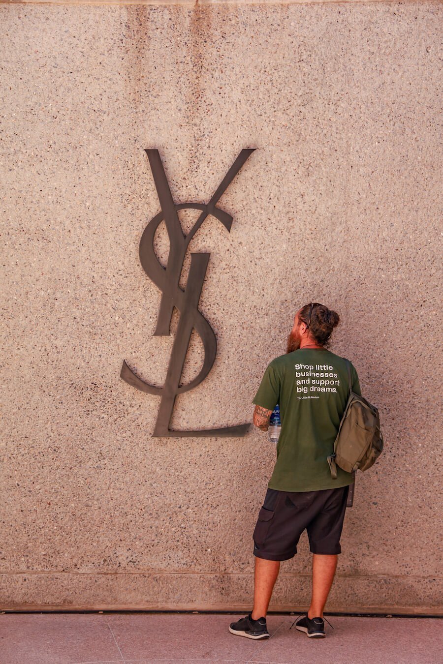 A man stands in front the Yves Saint Laurent sign at the YSL Museum in Marrakech, Morocco