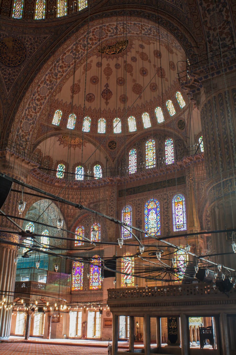 Inside the blue mosque with stained glass windows, domes and tiles.