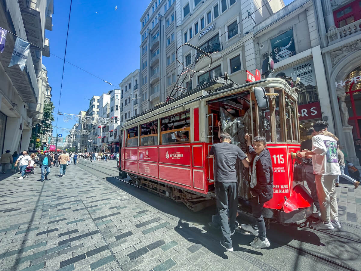 Kids catch a free ride off the back of the red tram on Istiklal Avenue in Istanbul