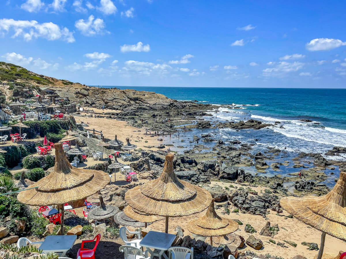 Tables and straw umbrellas line the beach at Cape Spartel.