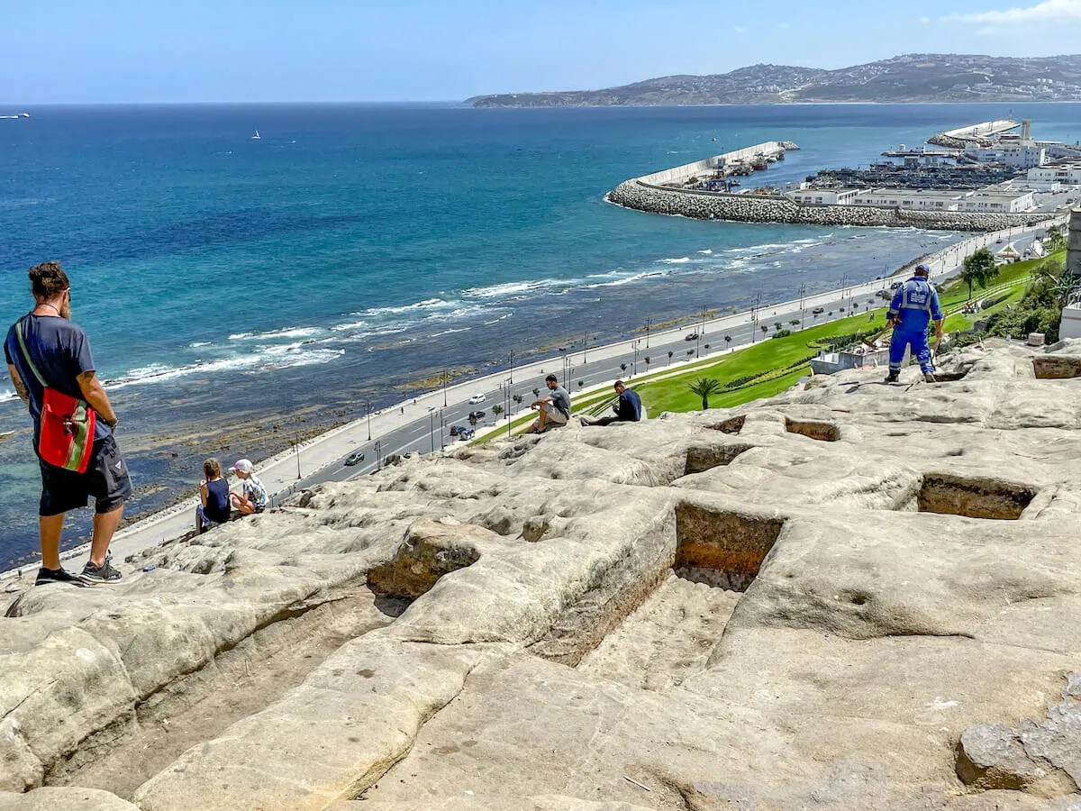 A family sit among the Phoenician Tombs in Tangier, Morocco while overlooking the Strait of Gibraltar towards Spain.