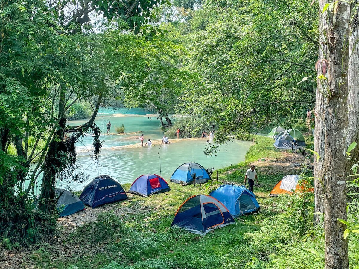 Tents dotted along the river bank at Agua Azul waterfalls in Palenque, Mexico