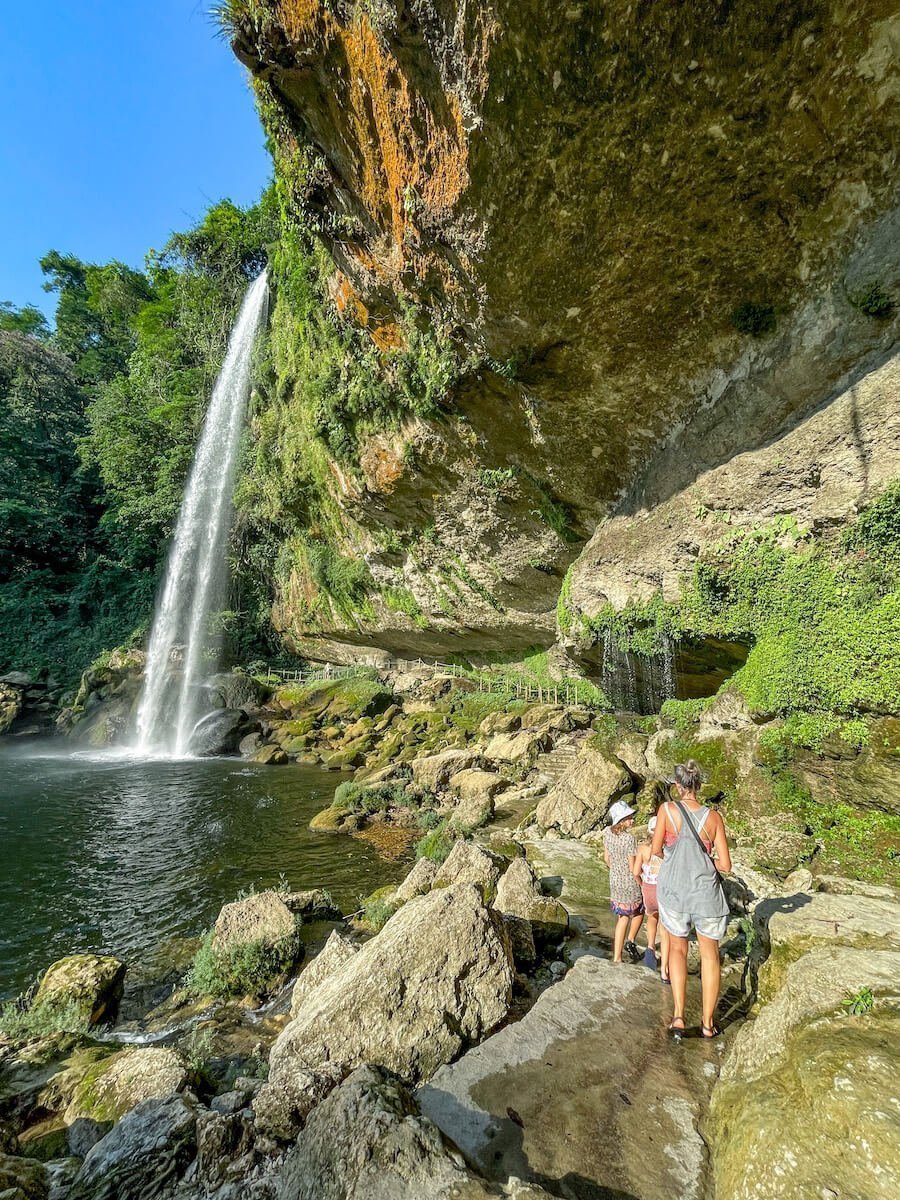 A lady and two young girls walk along a lush jungle track in Palenque, Mexico.