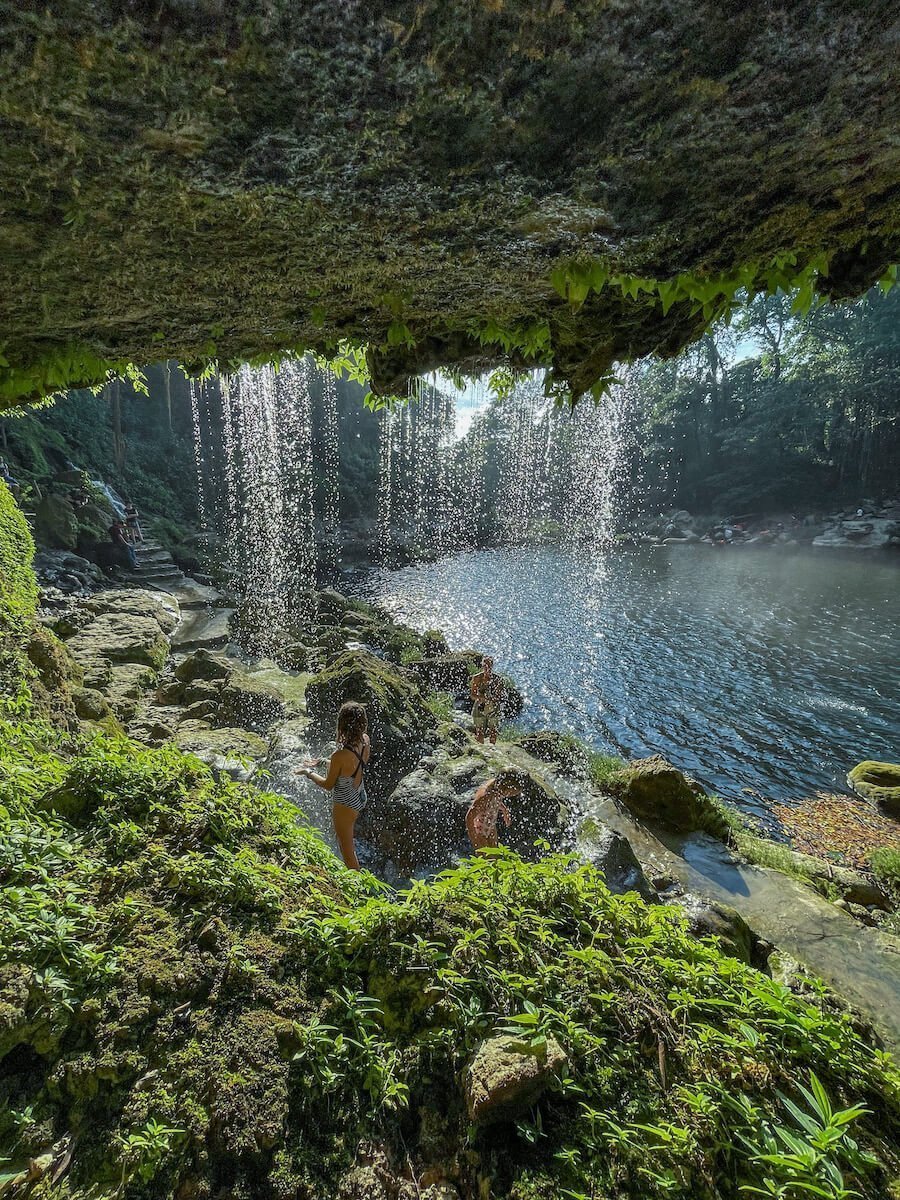 Two young girls playing under a small section of waterfall at Misol-Ha in Palenque. 