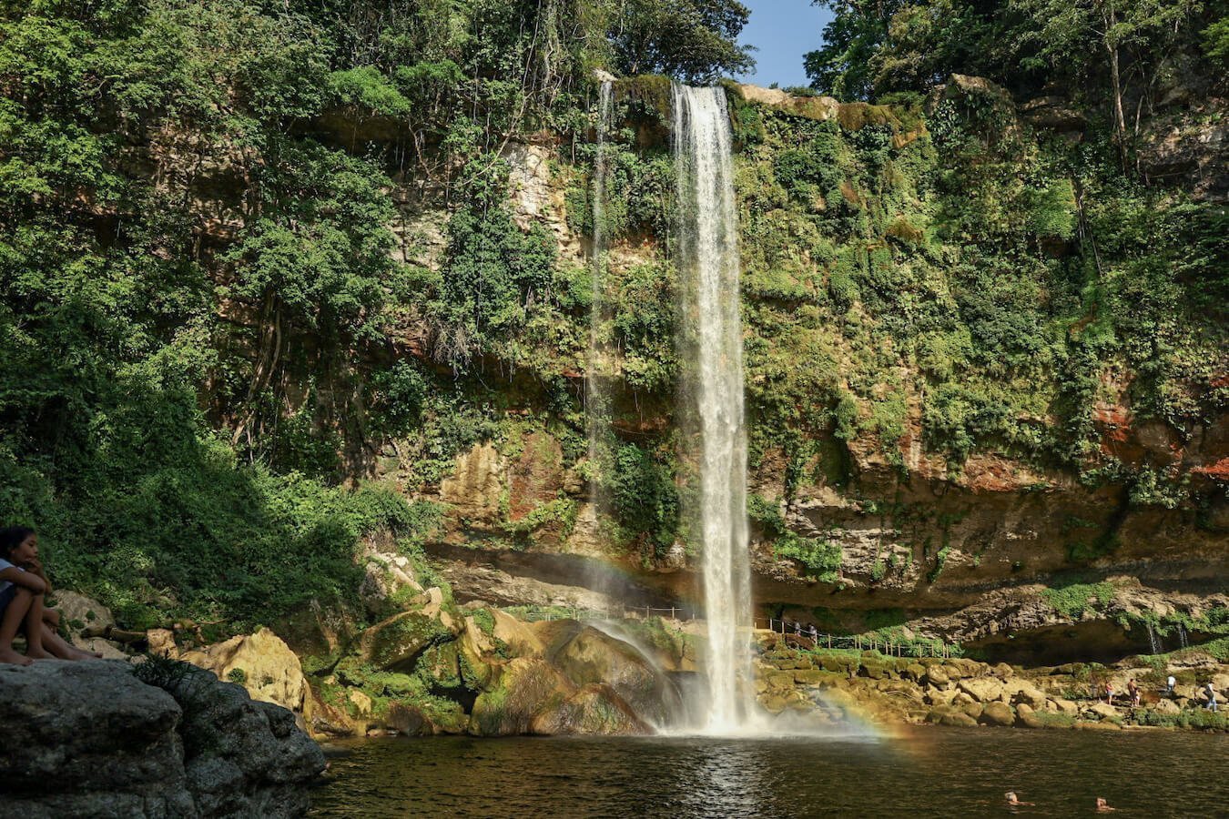 An image of the large waterfall at Misol-Ha, Palenque. Taken from down at the swimming hole, across the natural lagoon and with the walking track shown behind the waterfall.