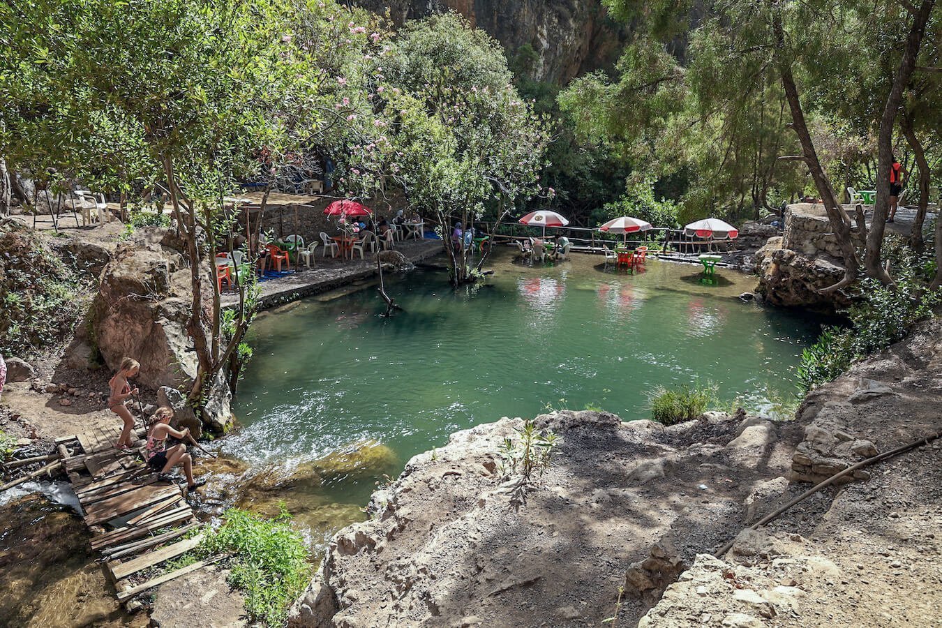 Holiday makers sit at the top of the petit or small waterfalls of Akchour on a God's Bridge day trip from Chefchaouen.