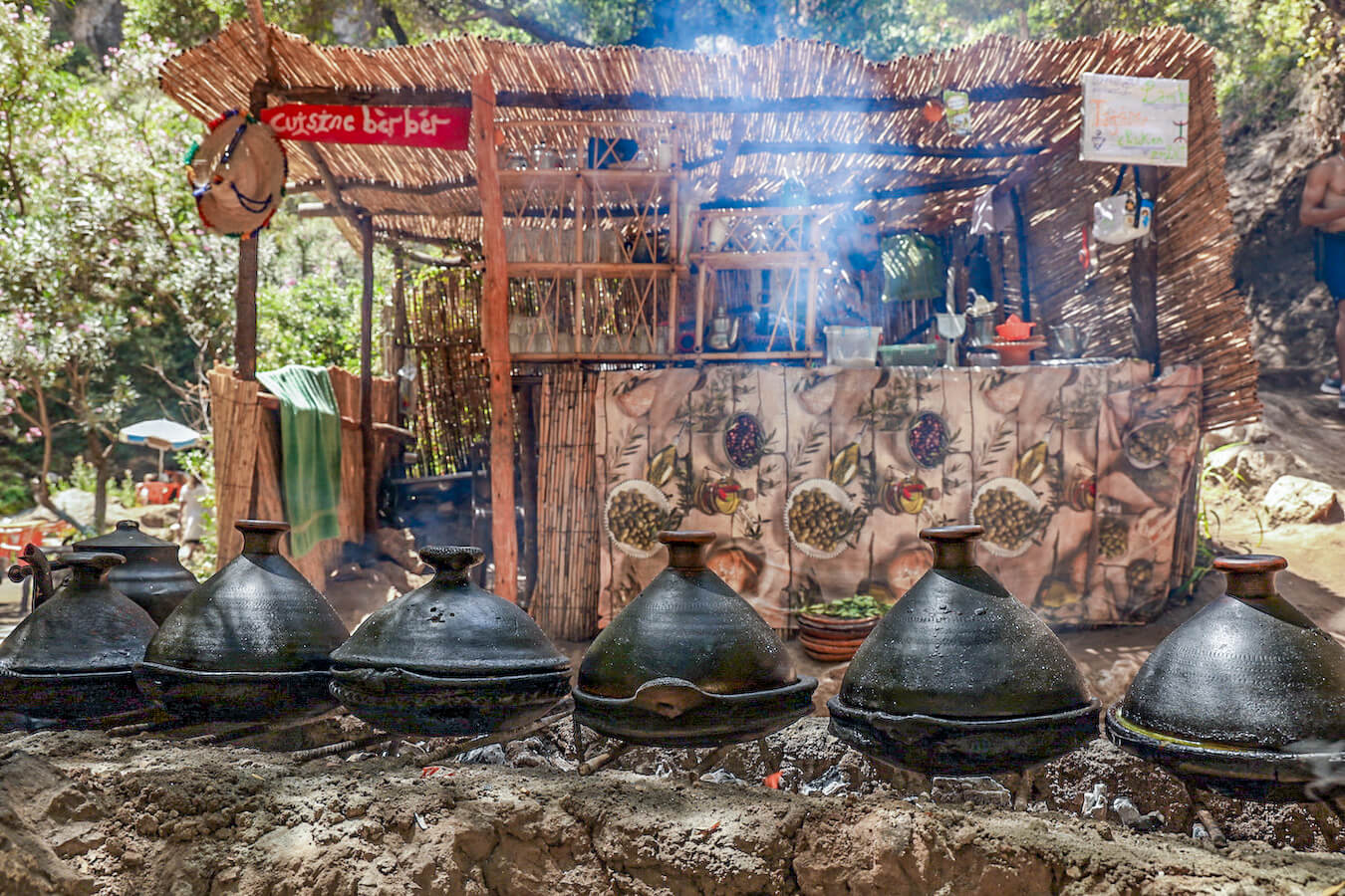 Tagines cook lined up over an open fire in front of the Cuisine Berber Restaurant on the Akchour trail towards the God's Bridge - a day trip from Chefchaouen