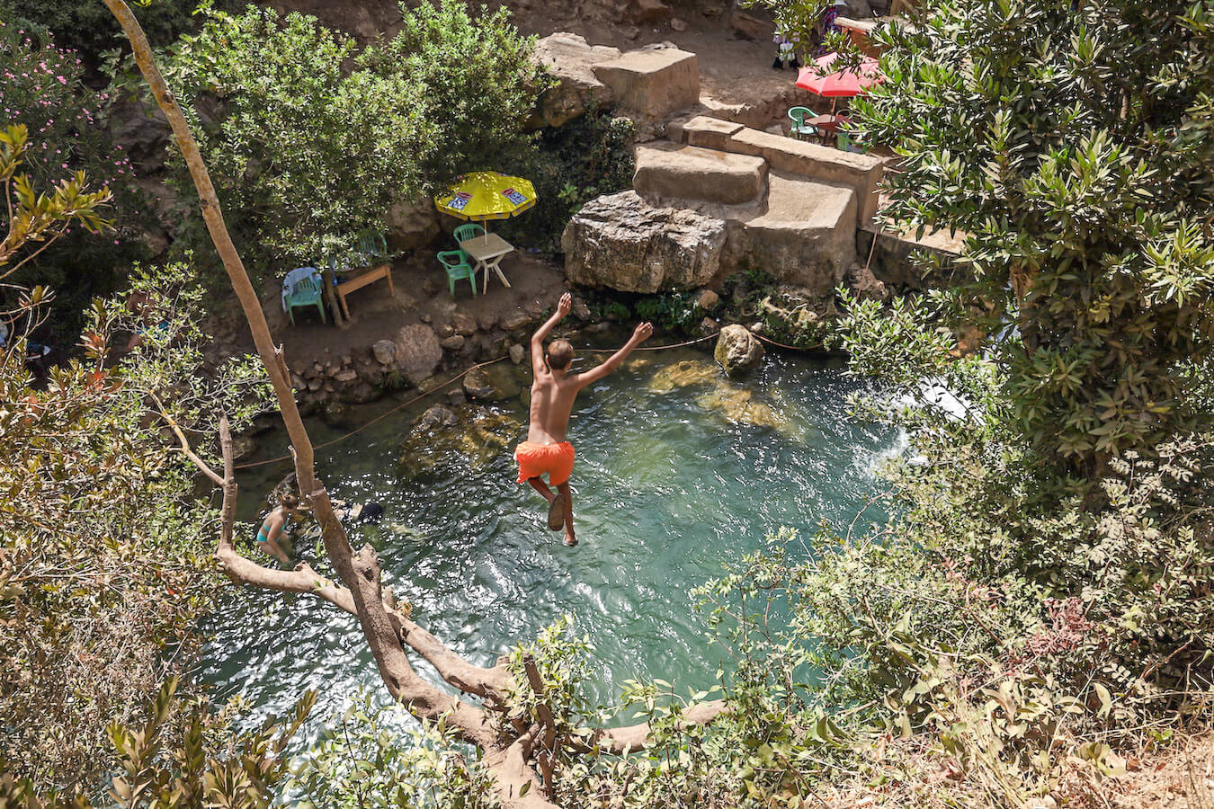 A child jumps into the river from a tree on the God's Bridge trail in Akchour