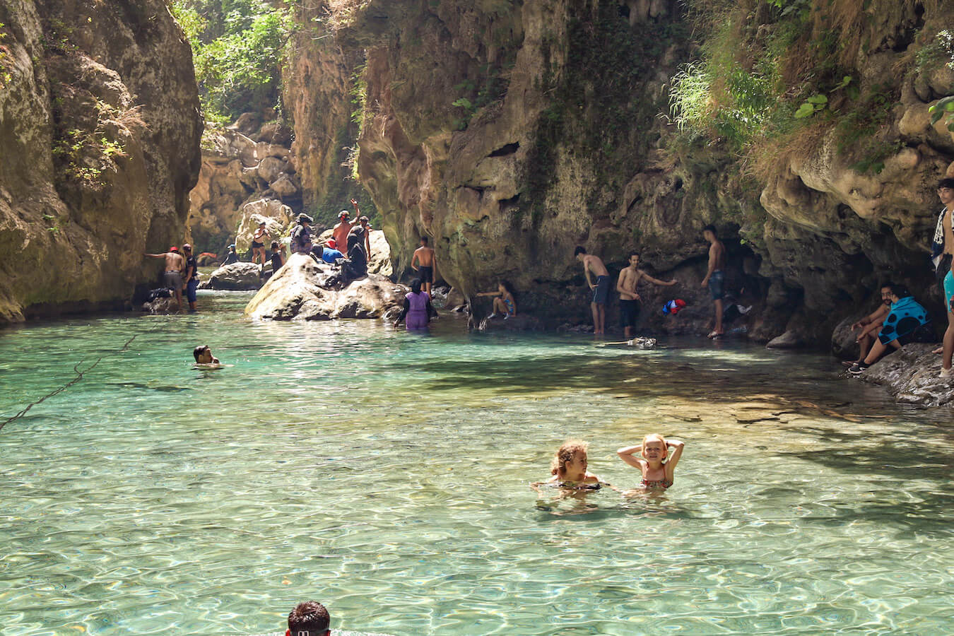 Summer holidaymakers swim under the natural arch in the clear river waters of God's Bridge in Akchour - a hidden gem of Chefchaouen