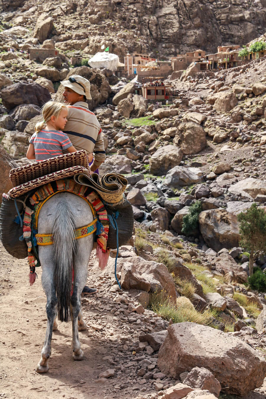 A child rides a mule with Trek Atlas Ahmed Zin near Sidi Chamharouch in the Atlas Mountains of Morocco