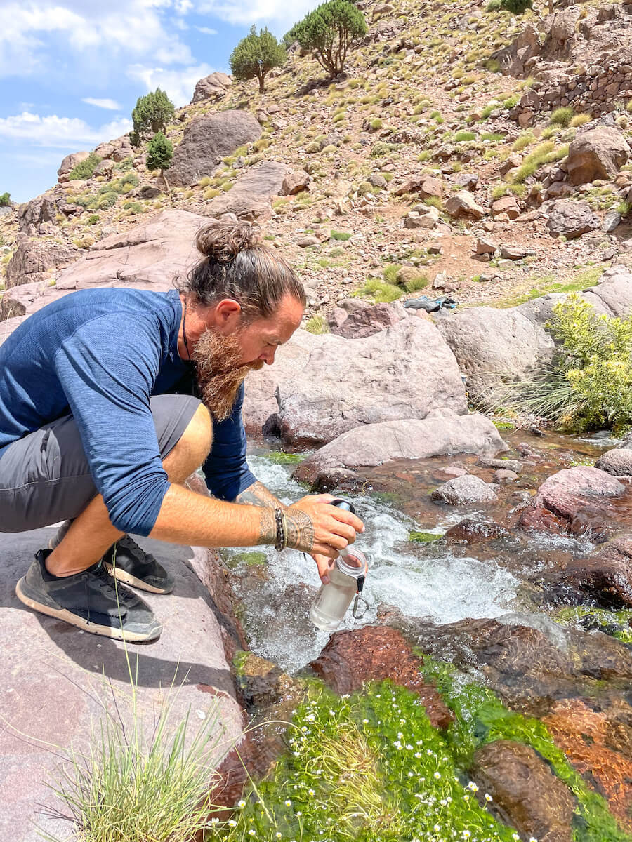 A man fills a Lifestraw bottle from a river in the Atlas Mountains of Morocco