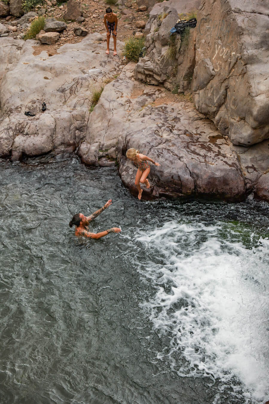 A father and daughter swim in a waterhole in the Atlas Mountain range in Morocco on a family tour