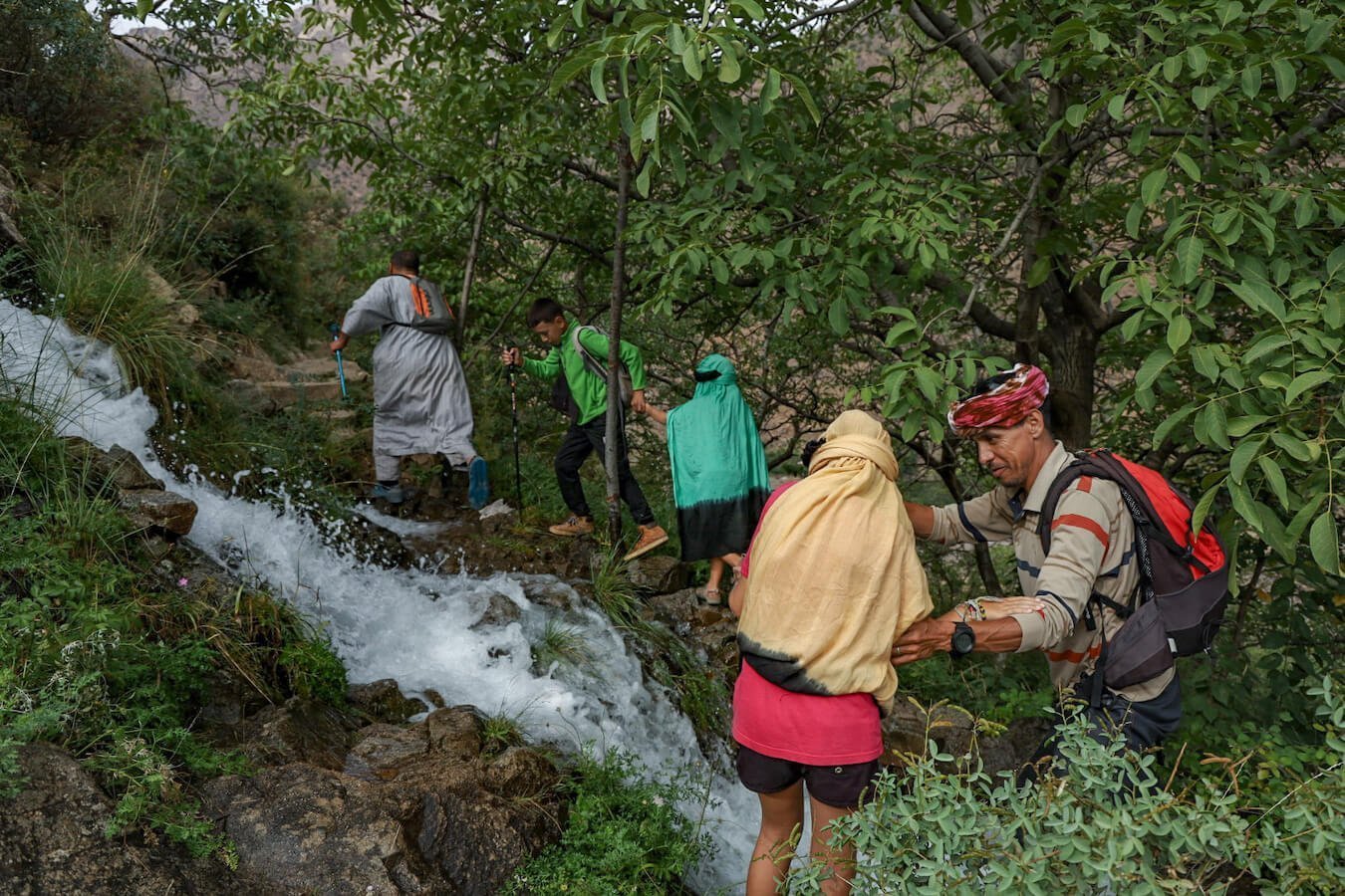 Ahmed Zin helps kids cross a waterfall on the Atlas Mountains in Morocco