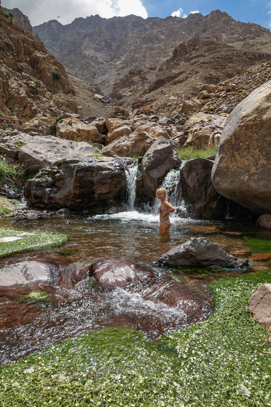 Kids swim in a waterfall in the Atlas Mountain range in Morocco on a family tour