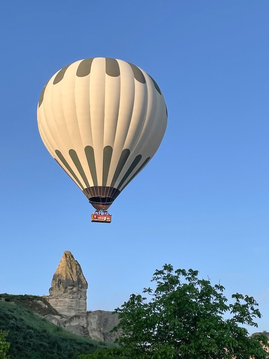 A hot air balloon flies over a fairy chimney in Cappadocia
