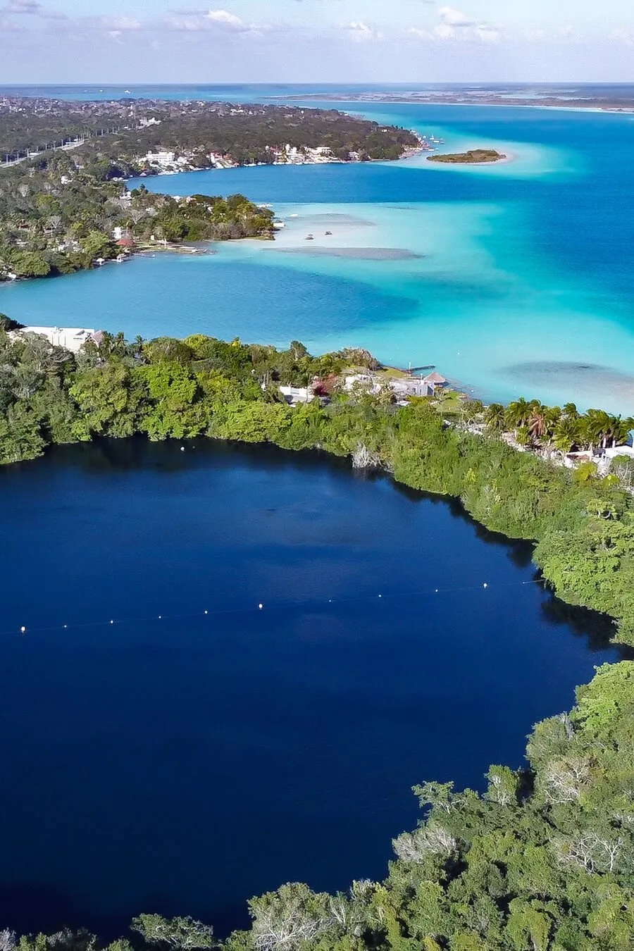 Drone image of the blended blue waters of the Bacalar Lagoon (AKA) Lake of Seven Colours. It's showing Cenote Azul, Cenote Esmeralda and Cenote Cocalitos - things to do in Bacalar