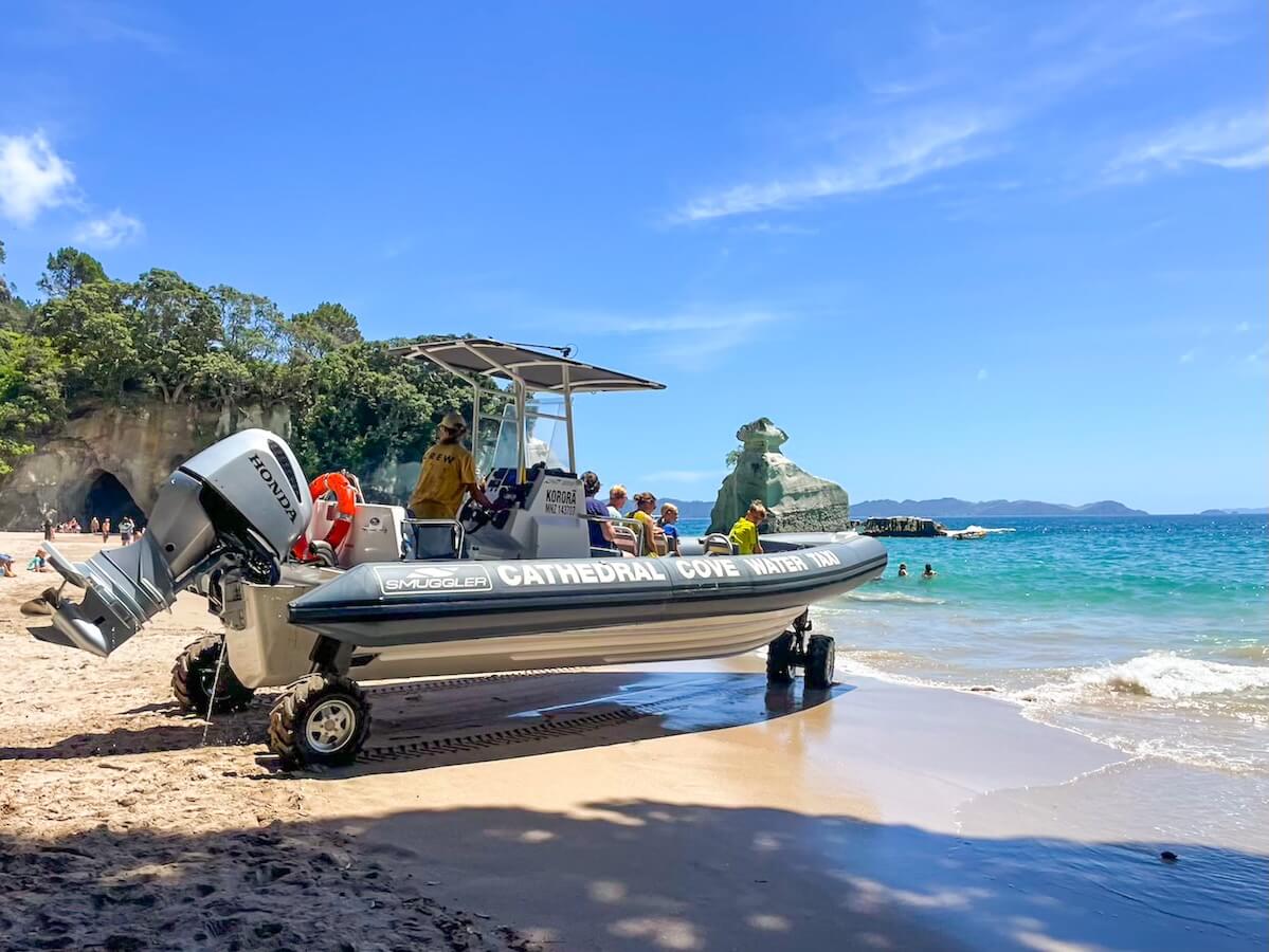 The Cathedral Cove Water Taxi boat waits for passengers while parked on the beach.