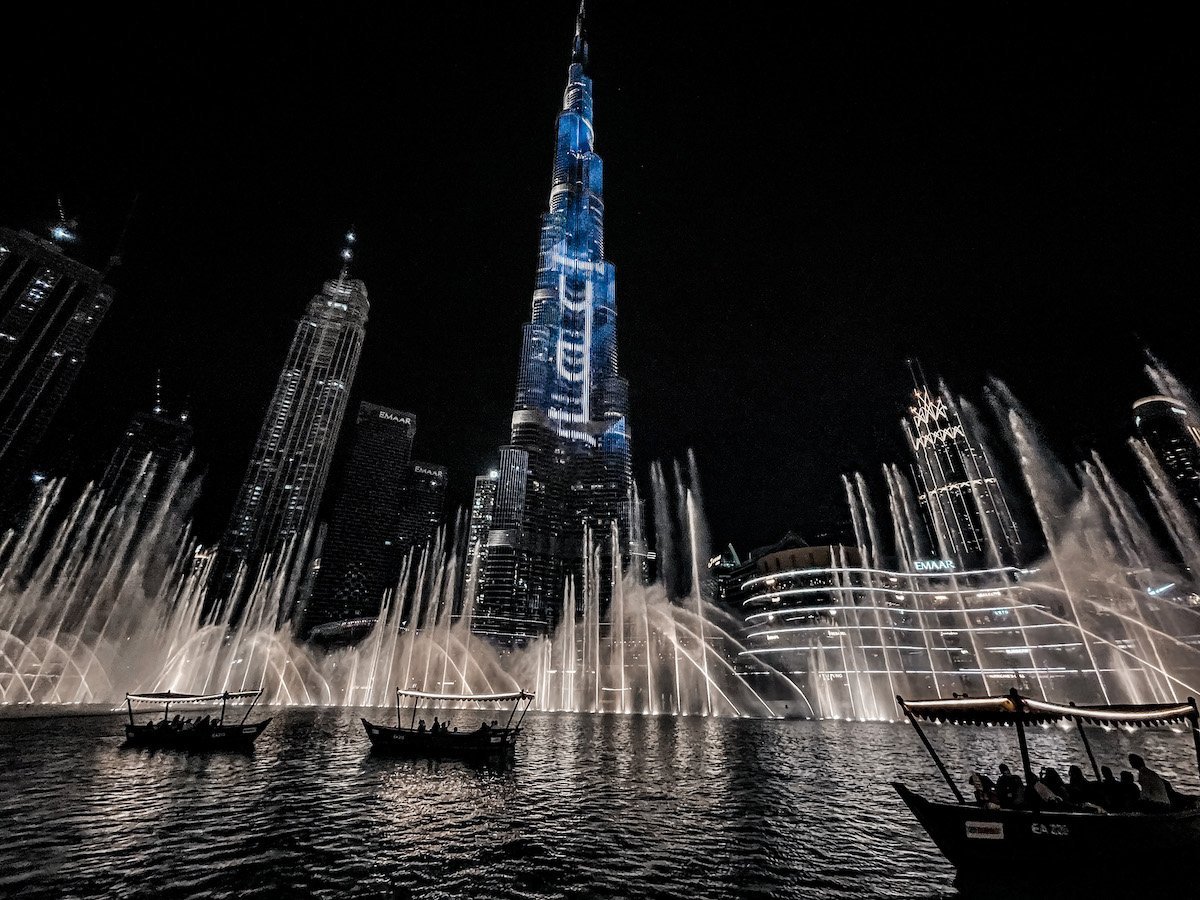 The Burj Khalifa in the background as the Dubai Fountains play in front.  Visitors sit in the abra and watch, an incredible place to visit