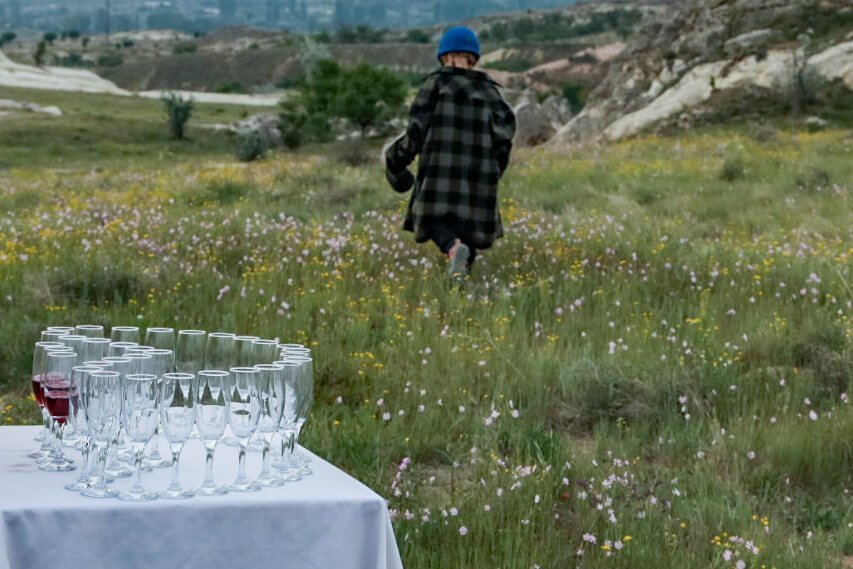 Child walks among wild flowers.  Champagne is prepared for the celebration drink after a balloon flight in turkey