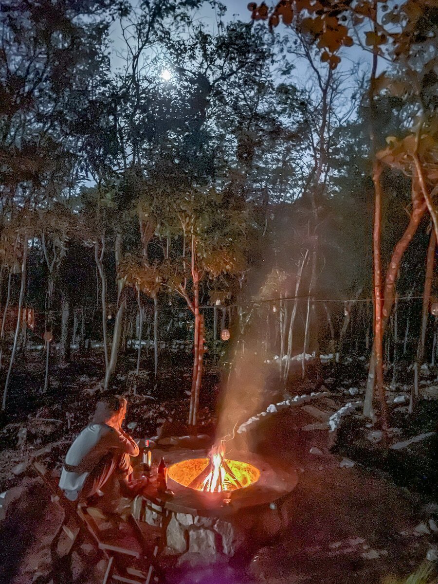 A woman sits at the fire pit at Cenote Secreto Maya near Valladolid on an overnight hotel stay.