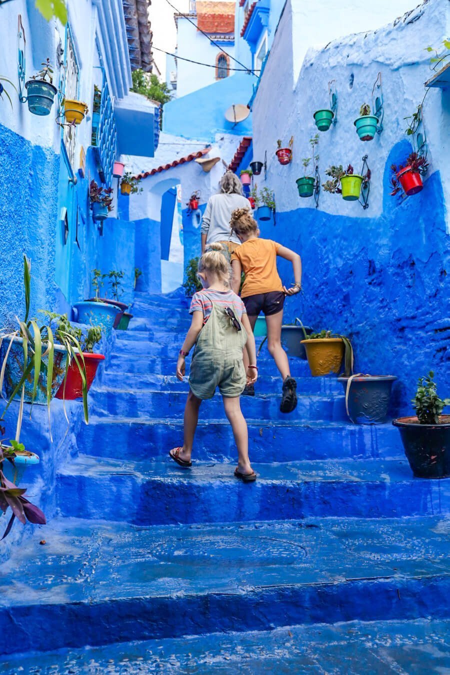 Kids walk through the blue streets in Chefchaouen - one of the most popular things to do on a Moroccan travel itinerary