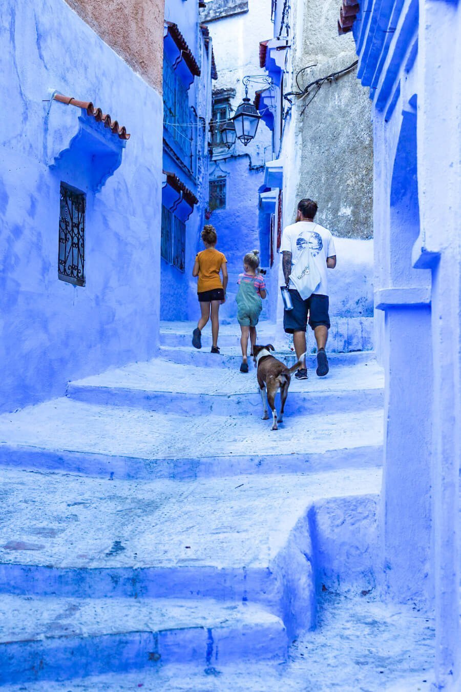 A father walks through the vibrant blue streets of Chefchaouen looking for top things to do in the village.