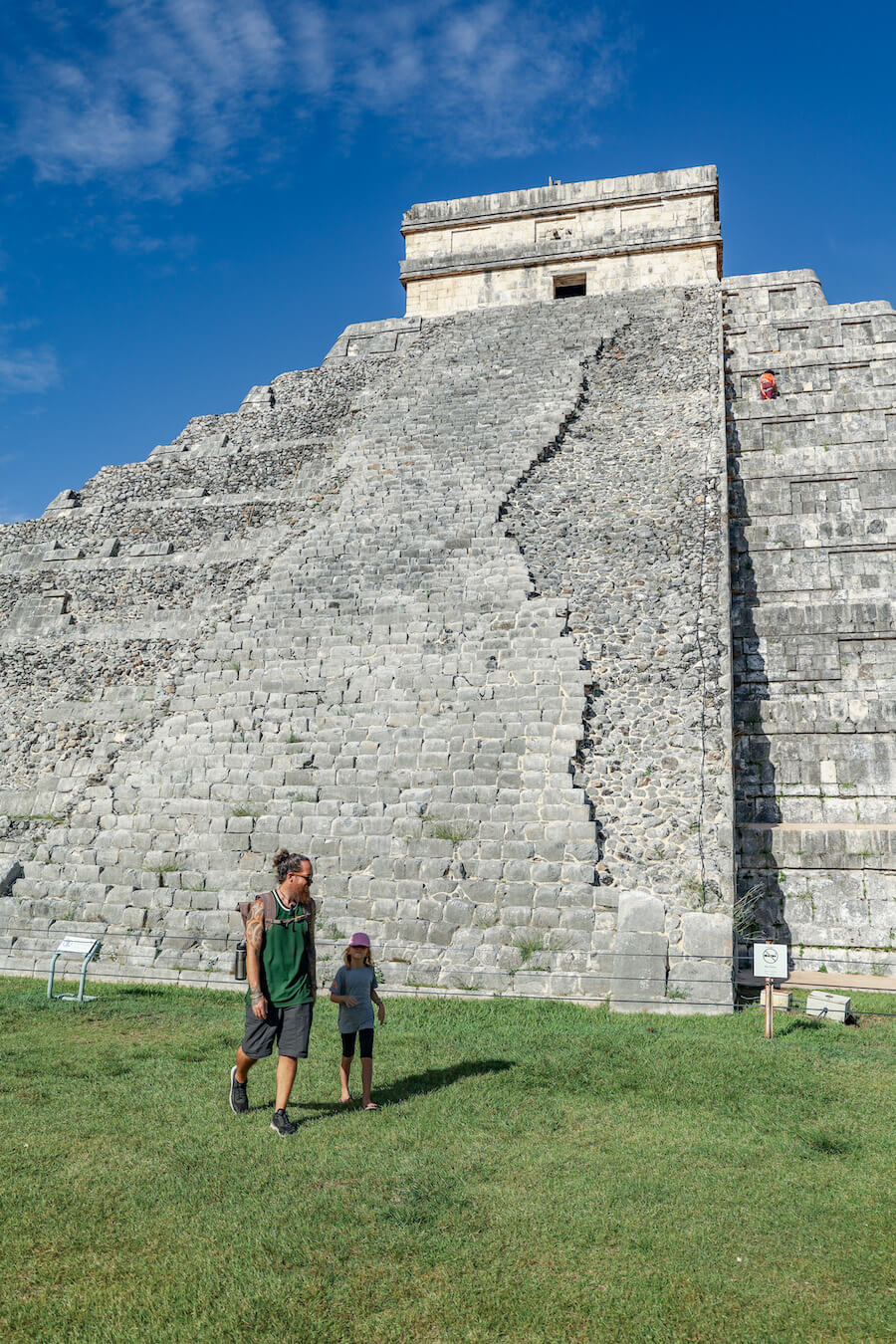 A father and his daughters walk in front of the Kukulkan Temple early in the morning at Chichén Itzá without many tourists.  Our self-guided tour helps visitors understand this impressive structure without an organised group tour 