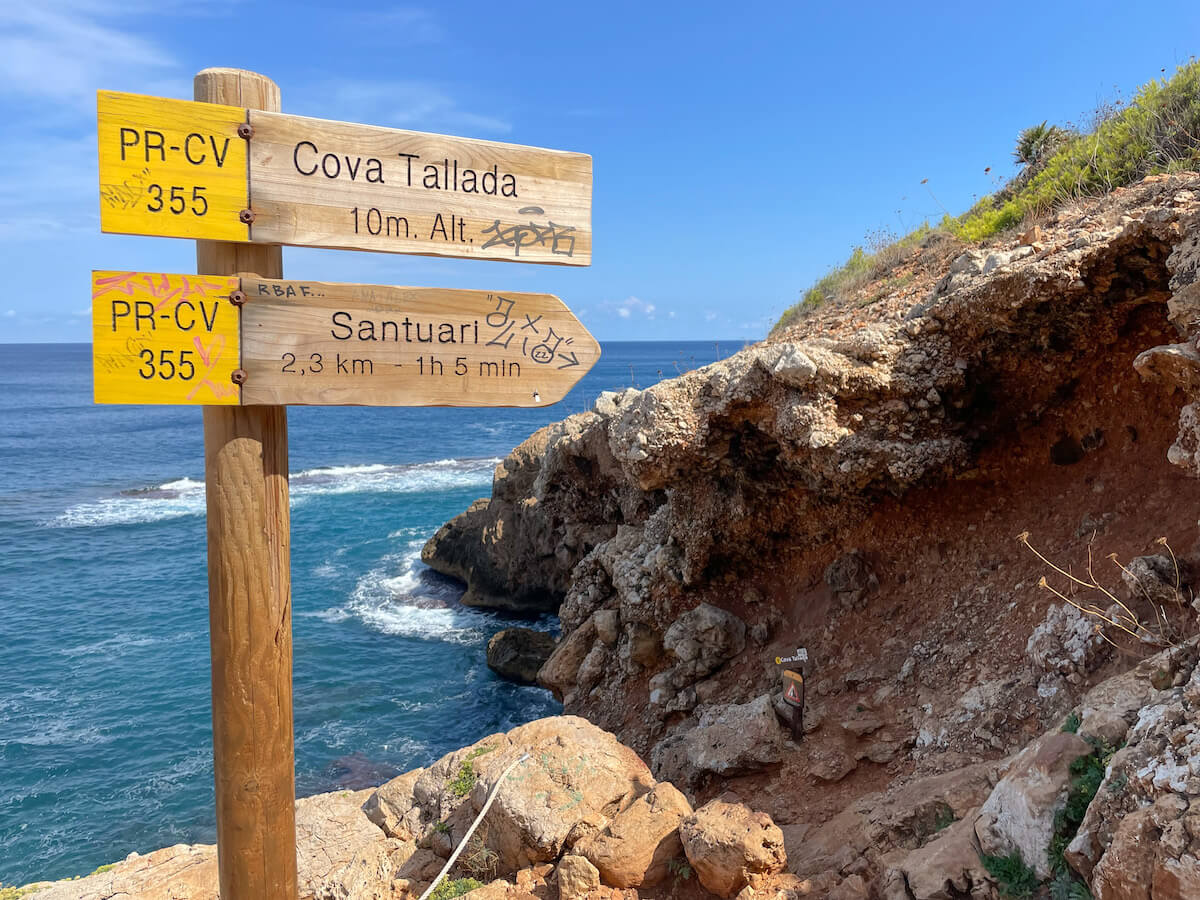 Sign posts to Cova Tallada caves on the PR CV 355 trail.