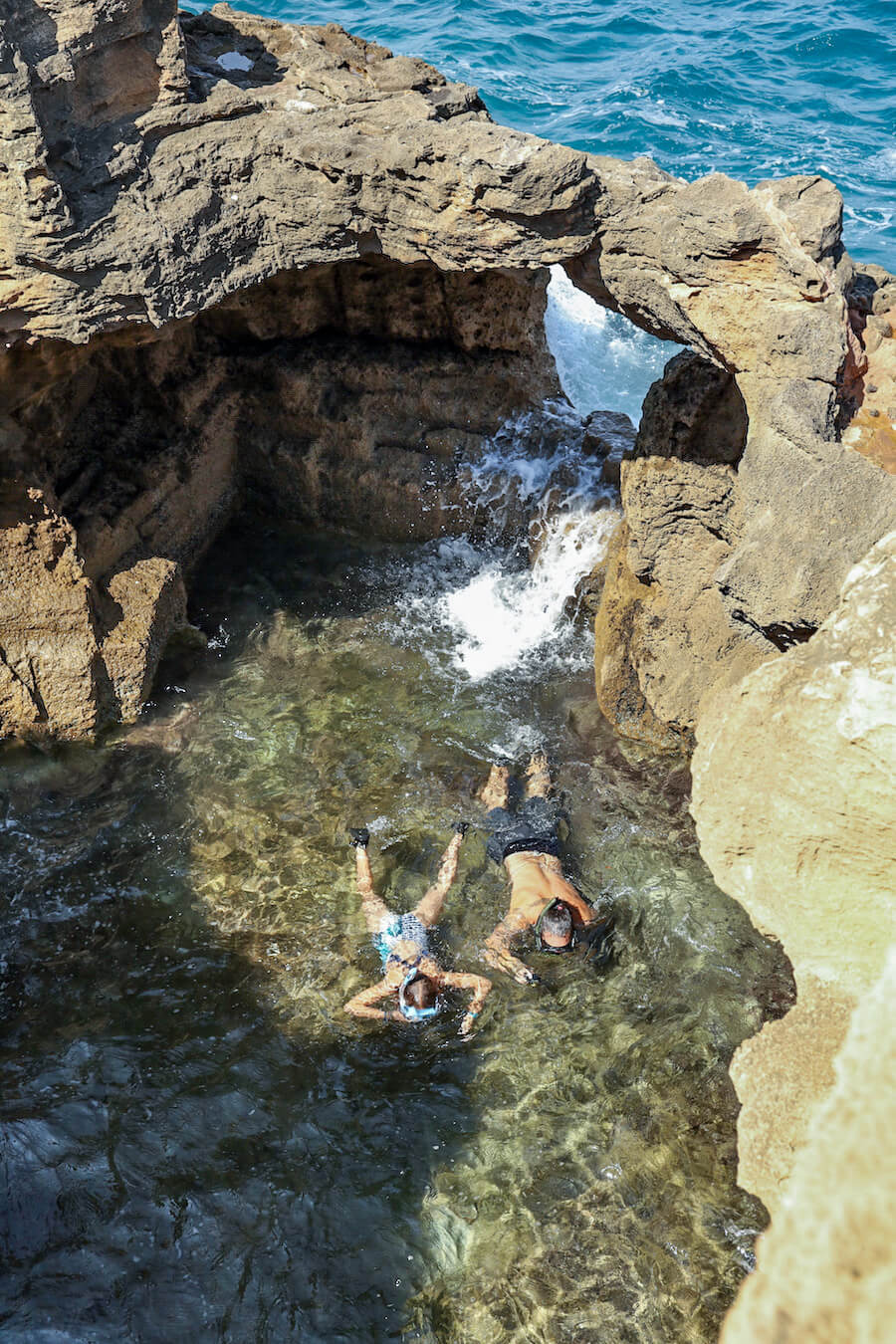 A father and daughter snorkel in the shallow lagoon of the sea caves in Cova Tallada near Denia and Javea / Xabia, Spain