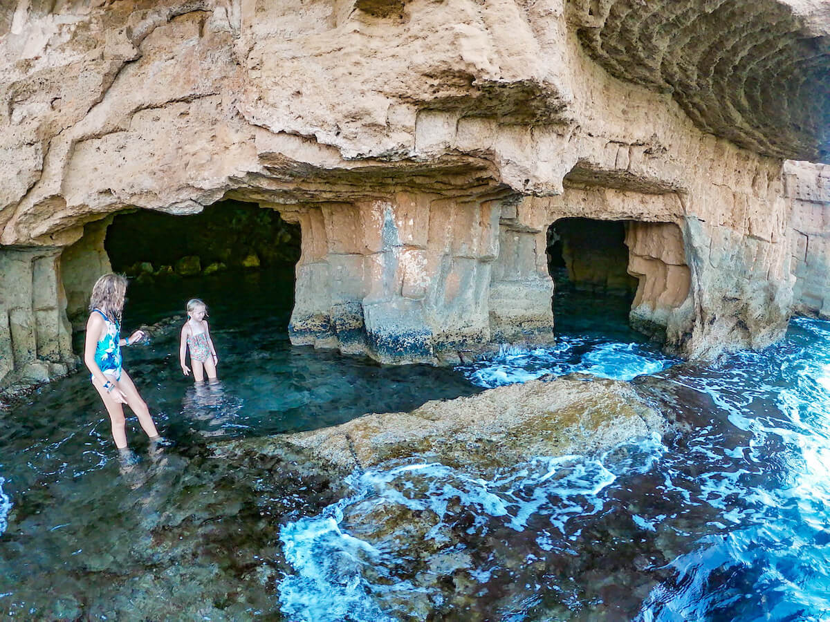 Kids wade through the sea caves of Cova Tallada in the Montgo Natural Park near Denia and Javea / Xabia in Spain
