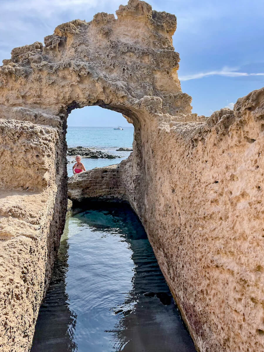 A woman looks through a hole carved into the rock at the Queen's Bath in Calpe, Spain.