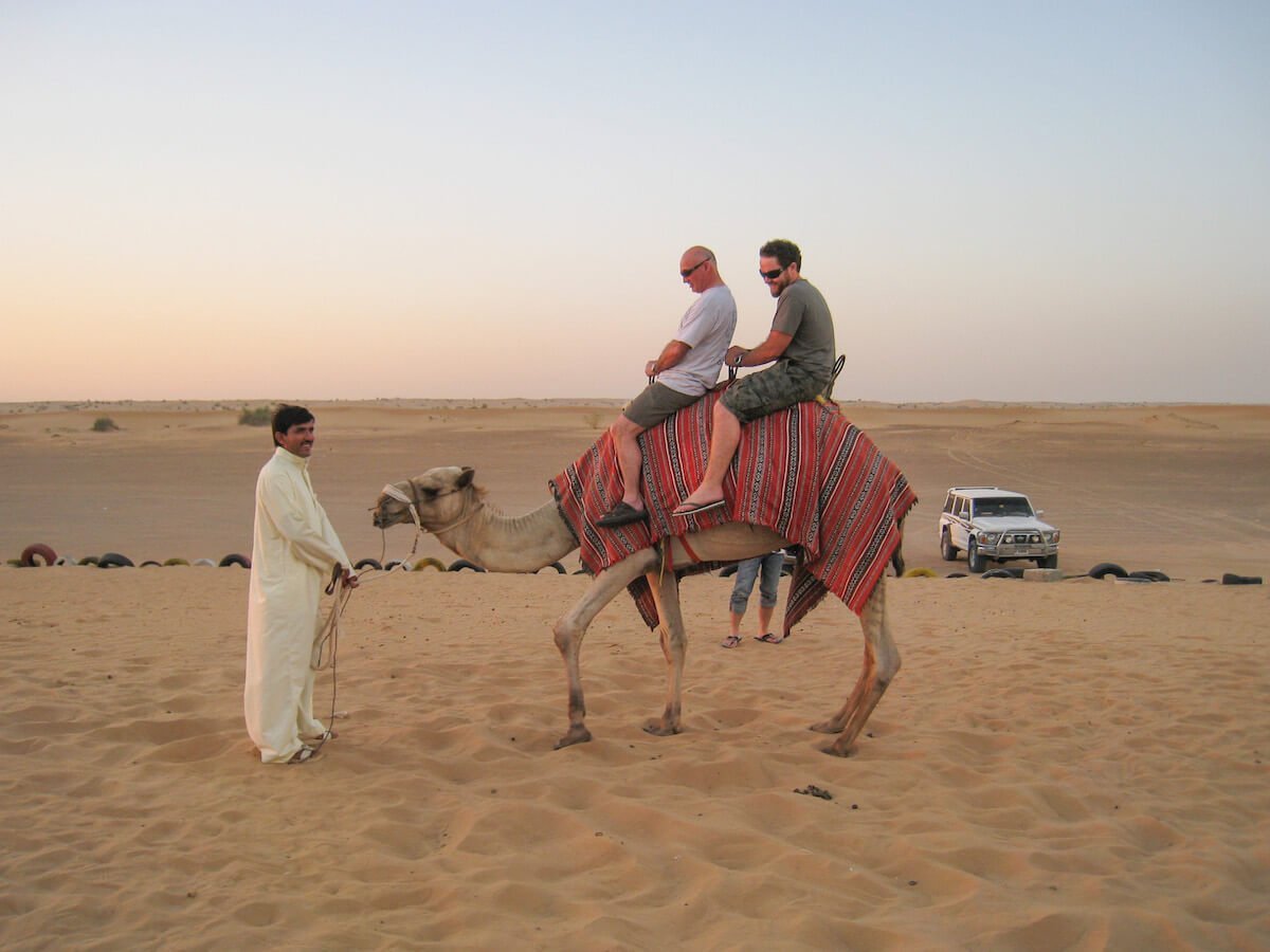 Men riding a camel in desert