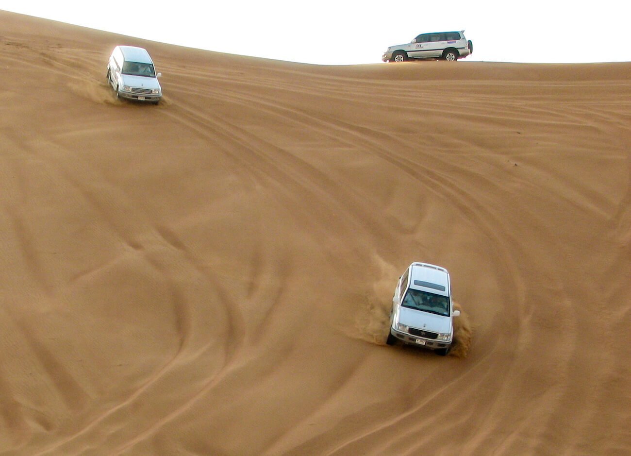 Desert Safari Dubai Landcruisers are dune bashing down the side of Big Red sand dunes