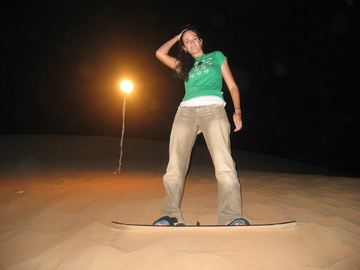 Girl sandboarding in the Dubai desert at night