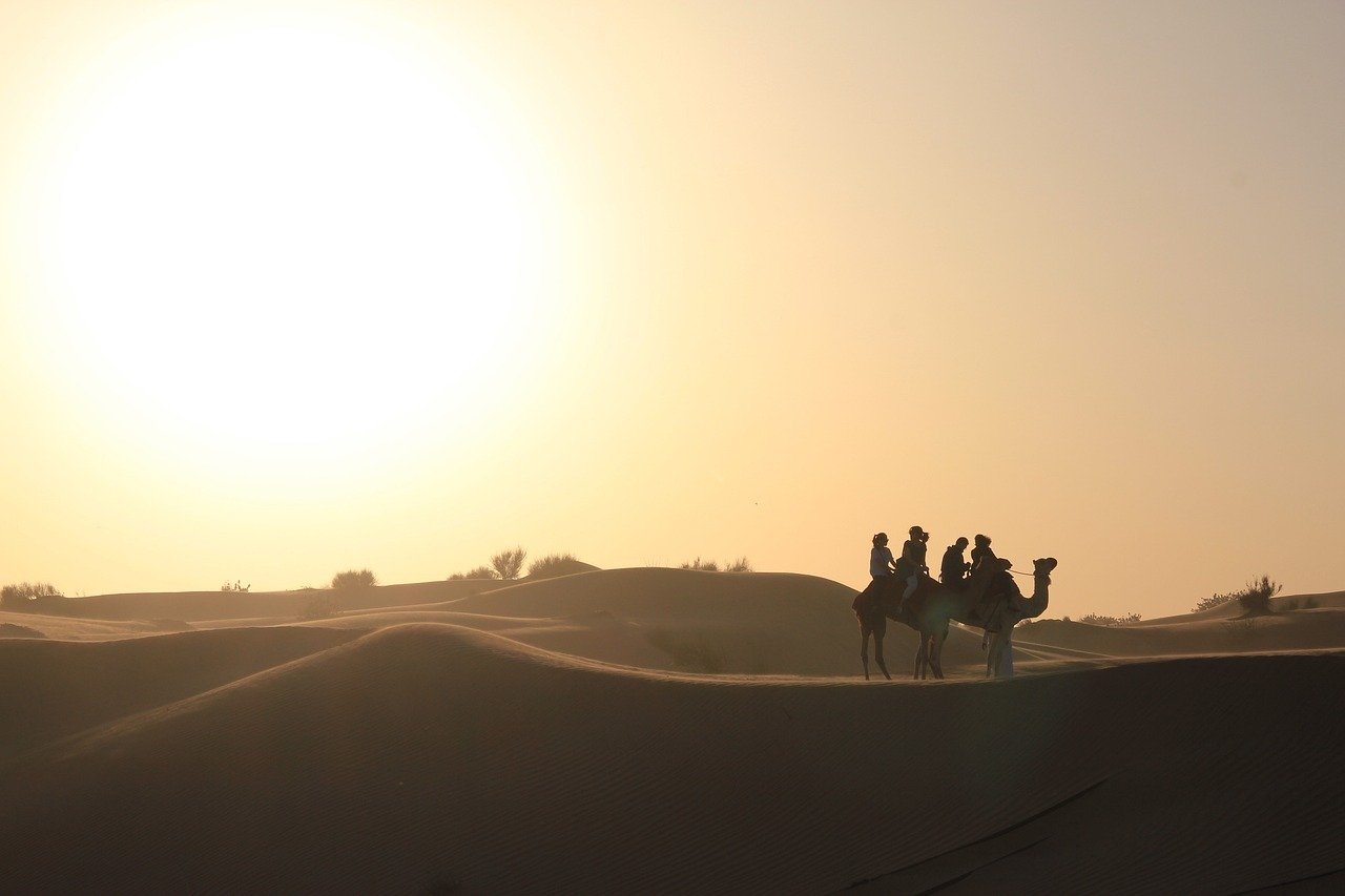Holiday makers ride camels on a Dubai Desert Safari Tour through the sand dunes