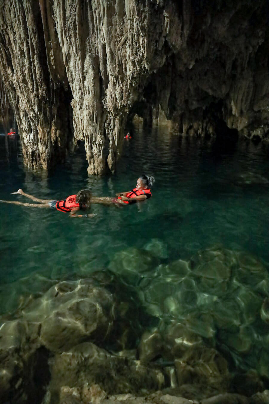 A month and child swim under the stalactites of Cenote Xkeken at Dzitnup near Valladolid