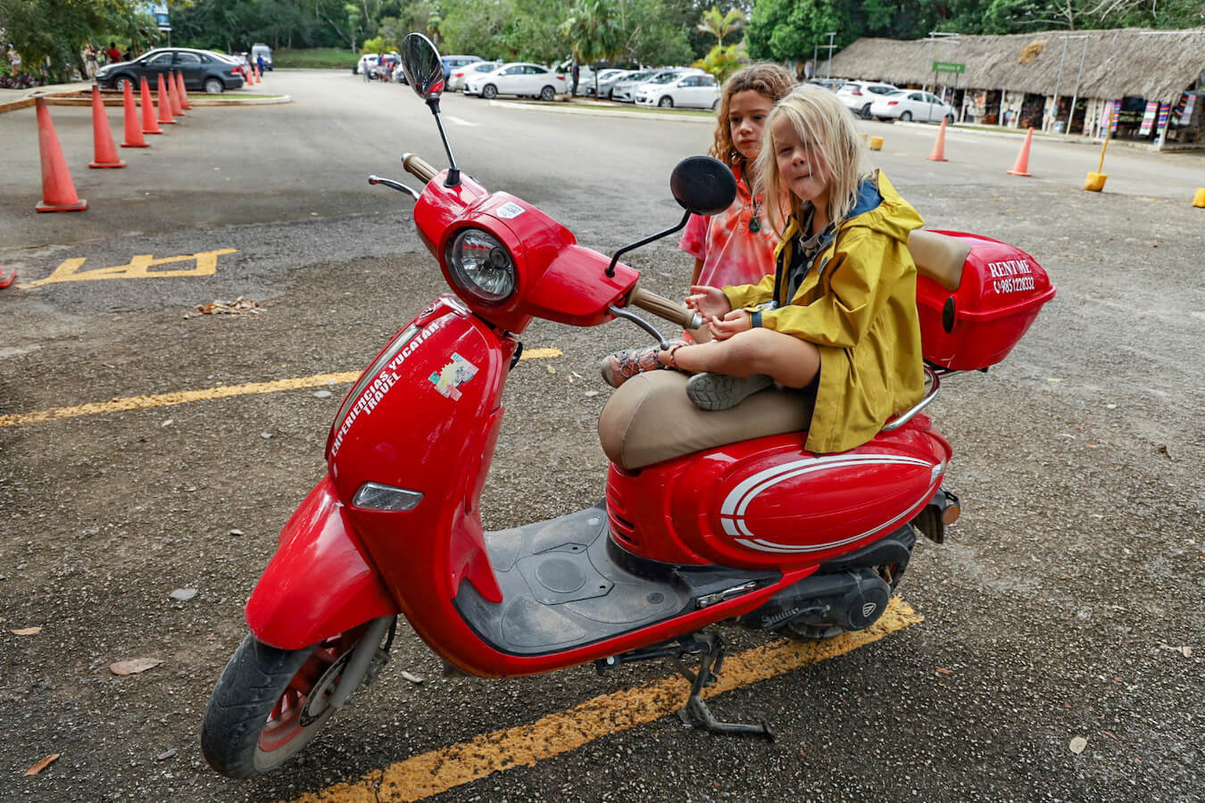 Kids sit on a rental scooter at the car park of Ek' Balam ruins ready for their visit - this is one of the best ways to get from Valladolid to Ek' Balam