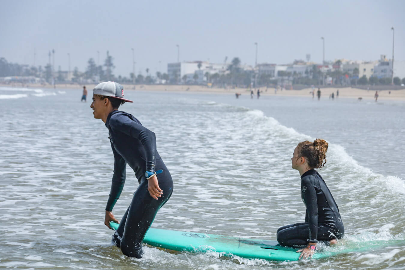 A surf instructor tows a kid into the surf in Essaouira Morocco