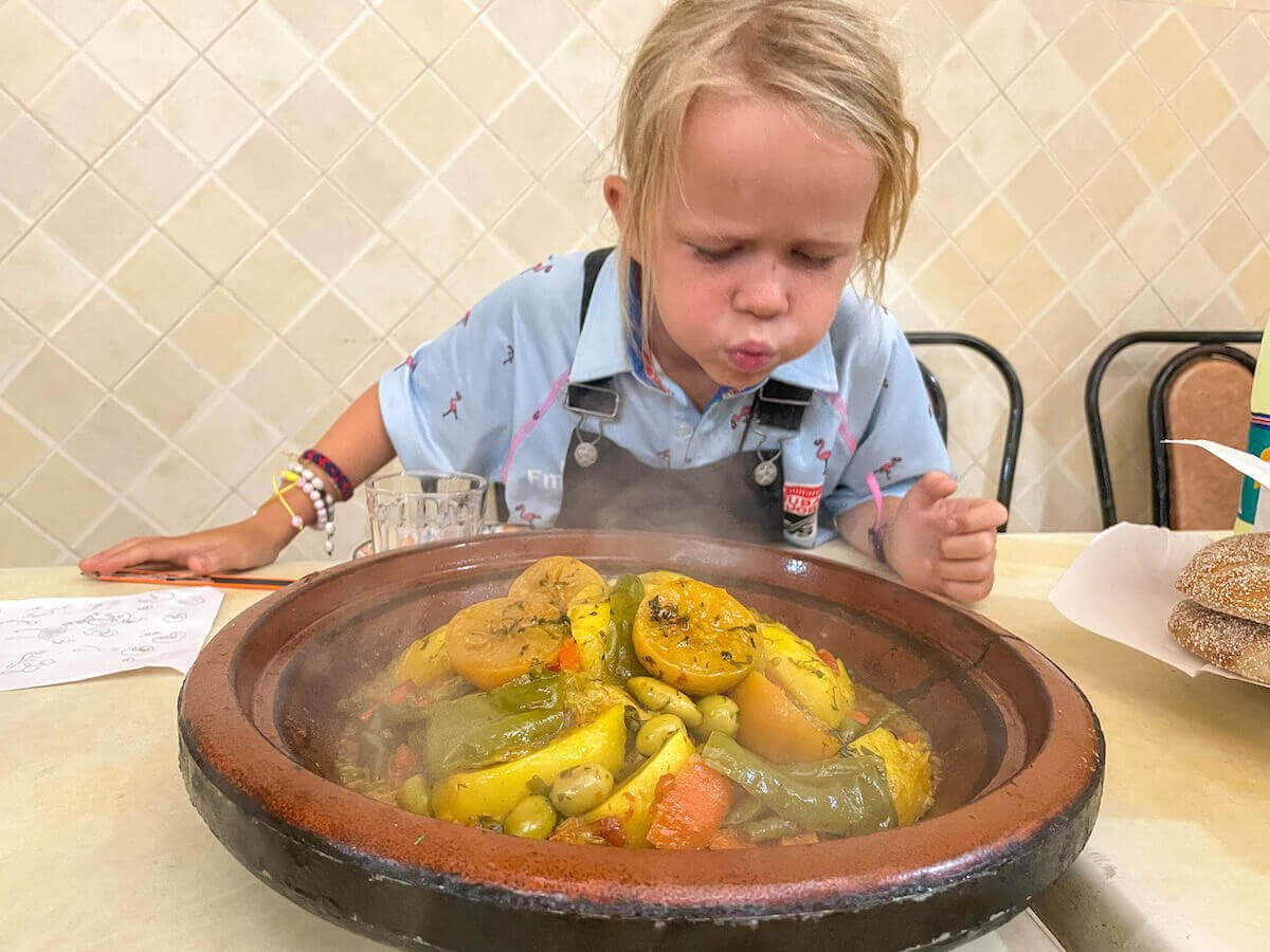 A kid looks at a hot tagine in Morocco