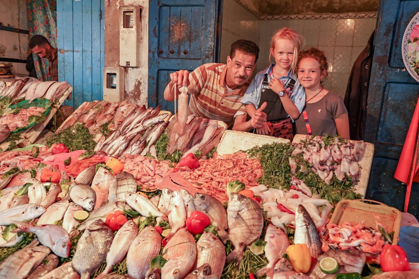 Kids pose for a photo at the fish market in Essaouira medina - a travel guide