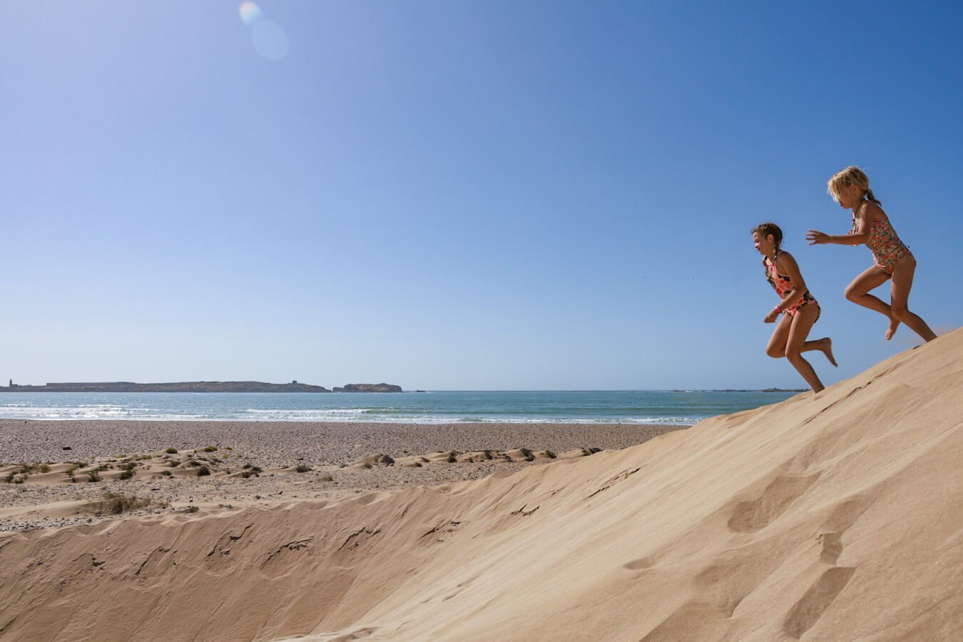 Kids play in the sand dunes in the best beaches of Essaouira - a travel guide