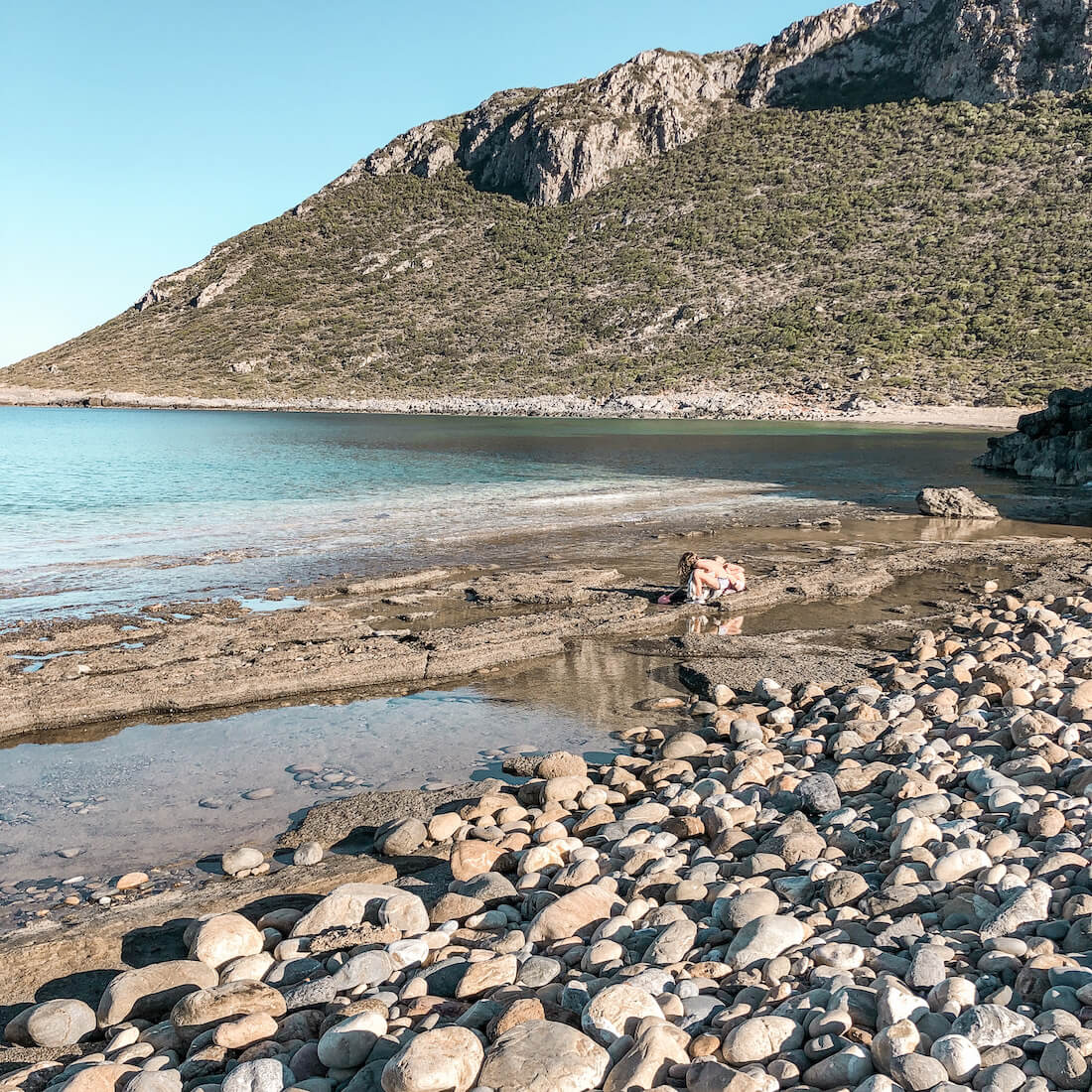Kids play on a rocky beach in the Peloponnese region of Greece